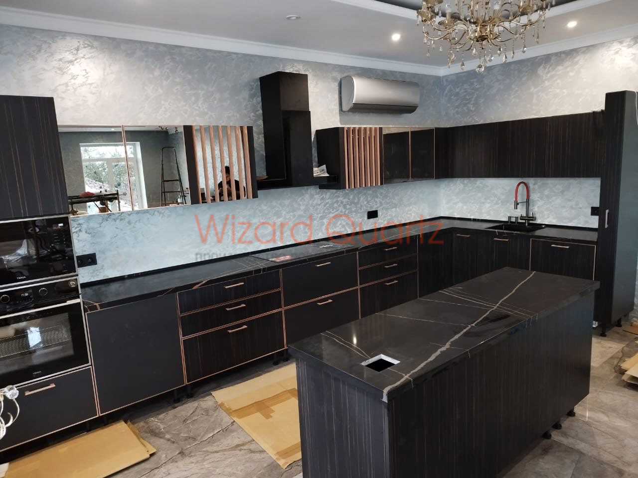 Г-образная столешница из кварцевого агломерата с островом темного цвета