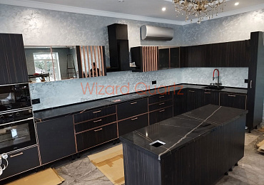 Г-образная столешница из кварцевого агломерата с островом темного цвета